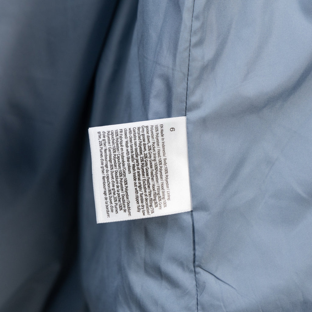 Light blue puffer vest with white care label on side seam