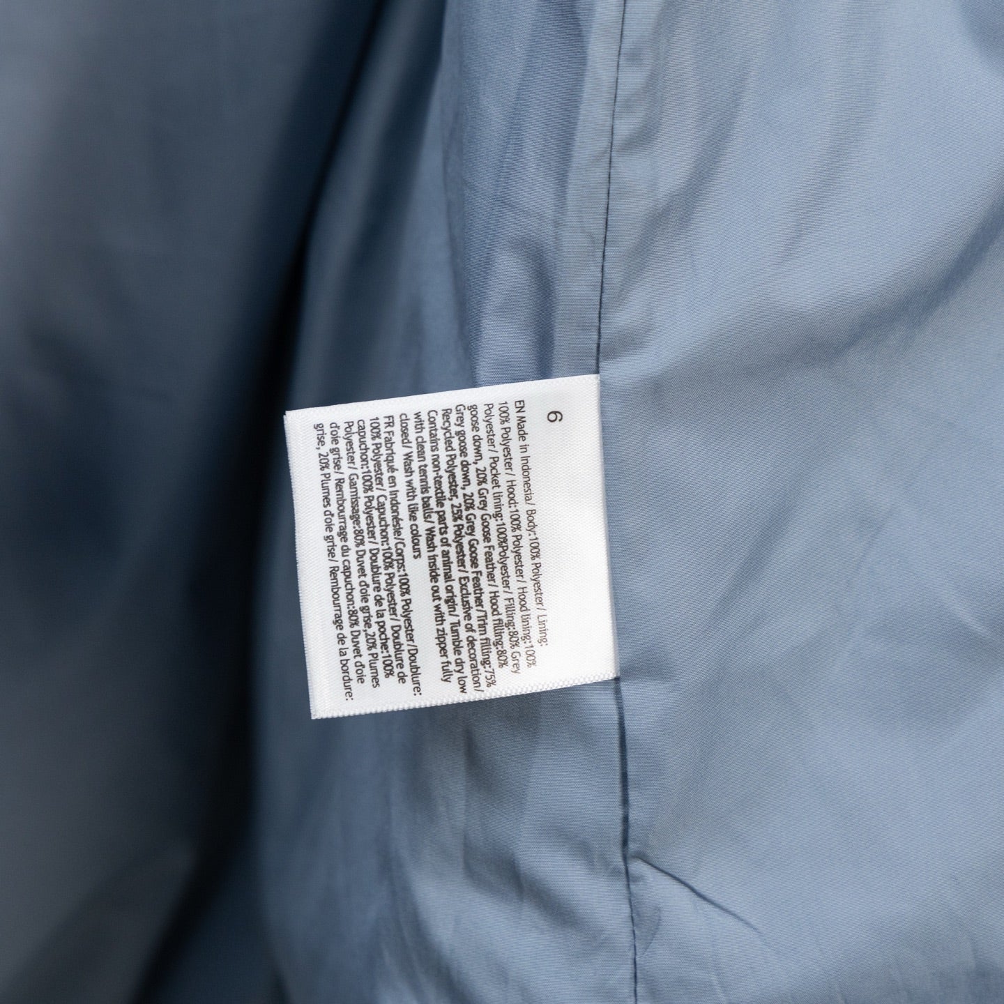 Light blue puffer vest with white care label on side seam