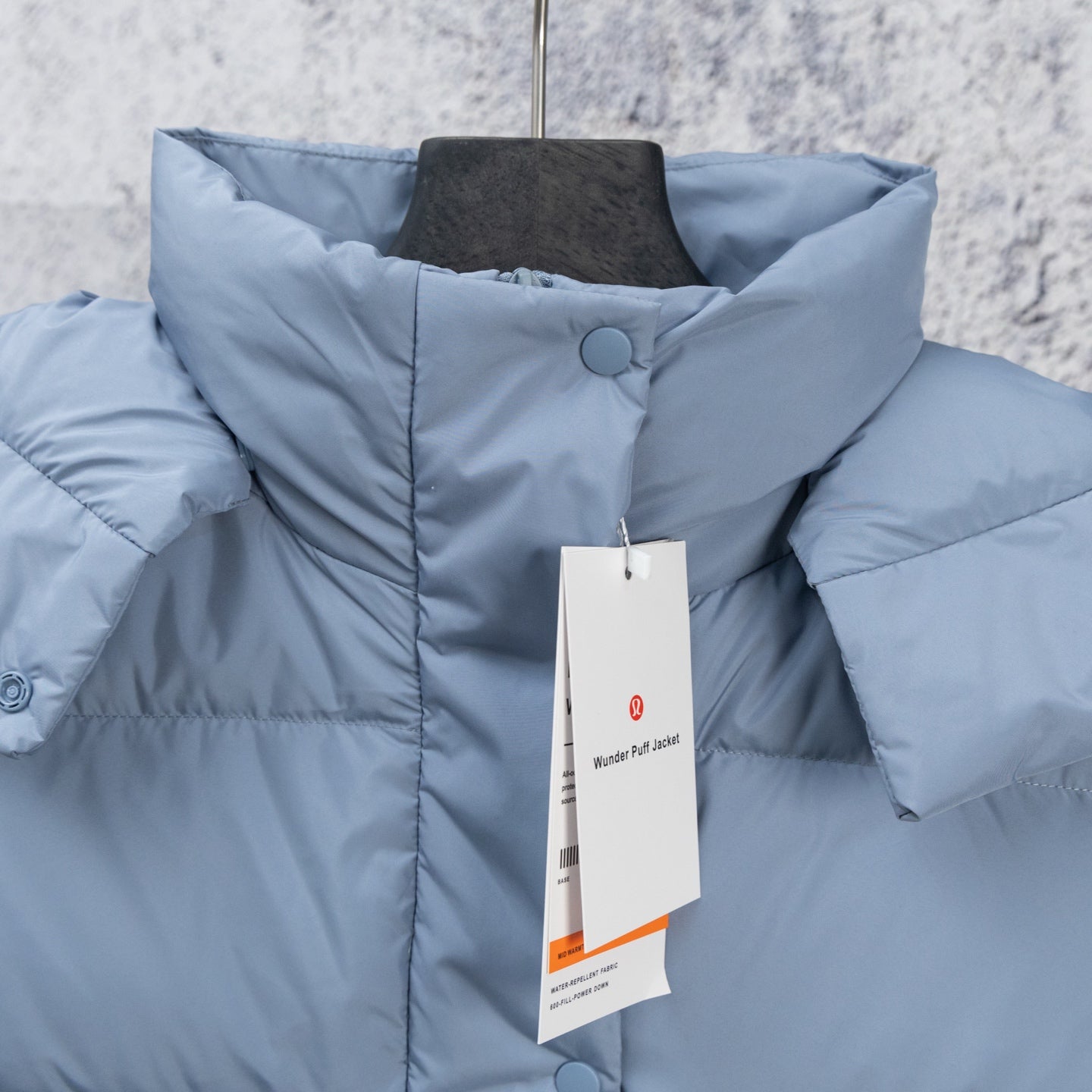 Light blue puffer vest close-up with stand collar and snap button placket