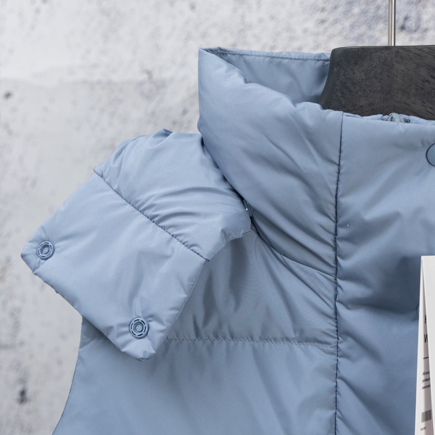 Light blue puffer vest with quilted shoulder panel and stitched flap detail