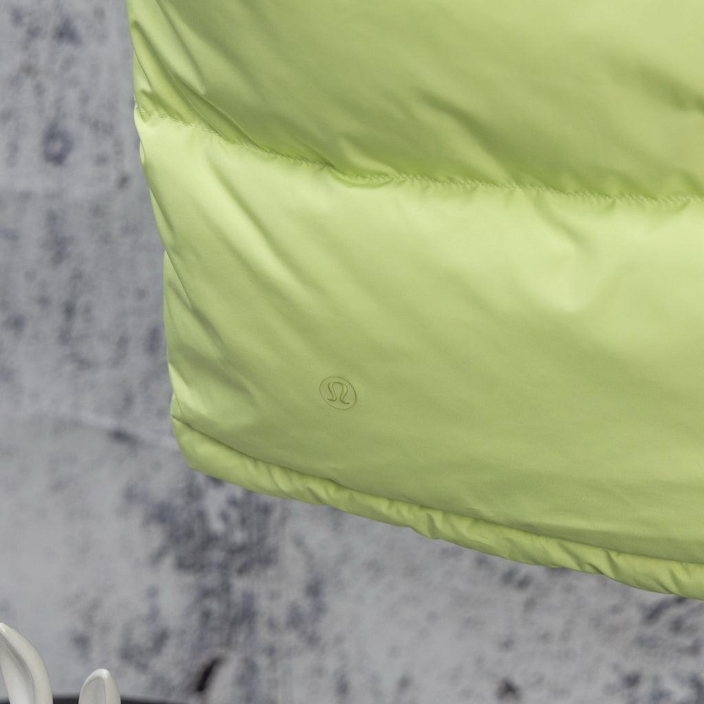 Lime green hooded puffer vest with logo patch on the front panel