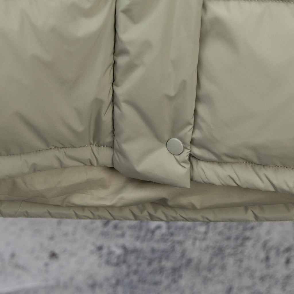 Light sage puffer vest hem with snap placket and round button detail