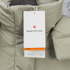 Light sage puffer vest fabric close-up with hanging “Wunder Puff Jacket” tag