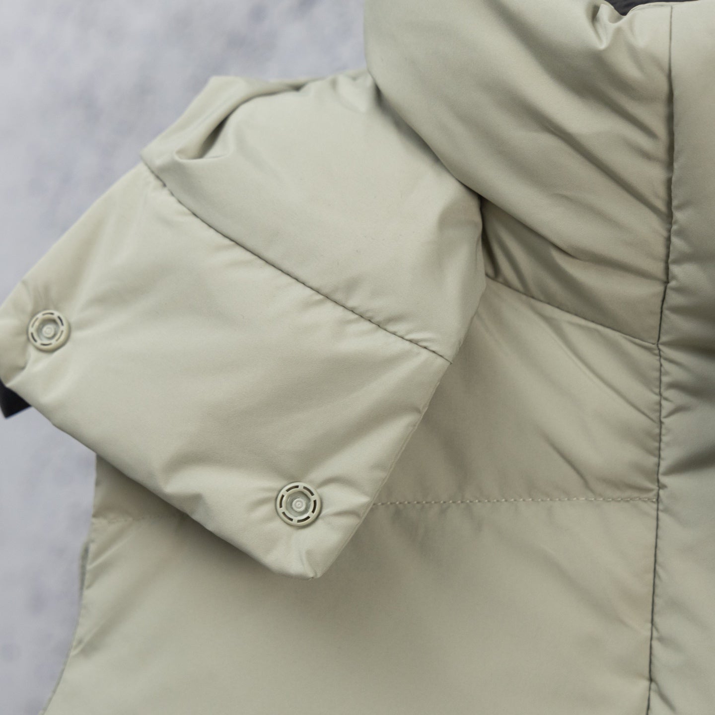 Light sage puffer vest sleeve area with snap buttons at the cuff