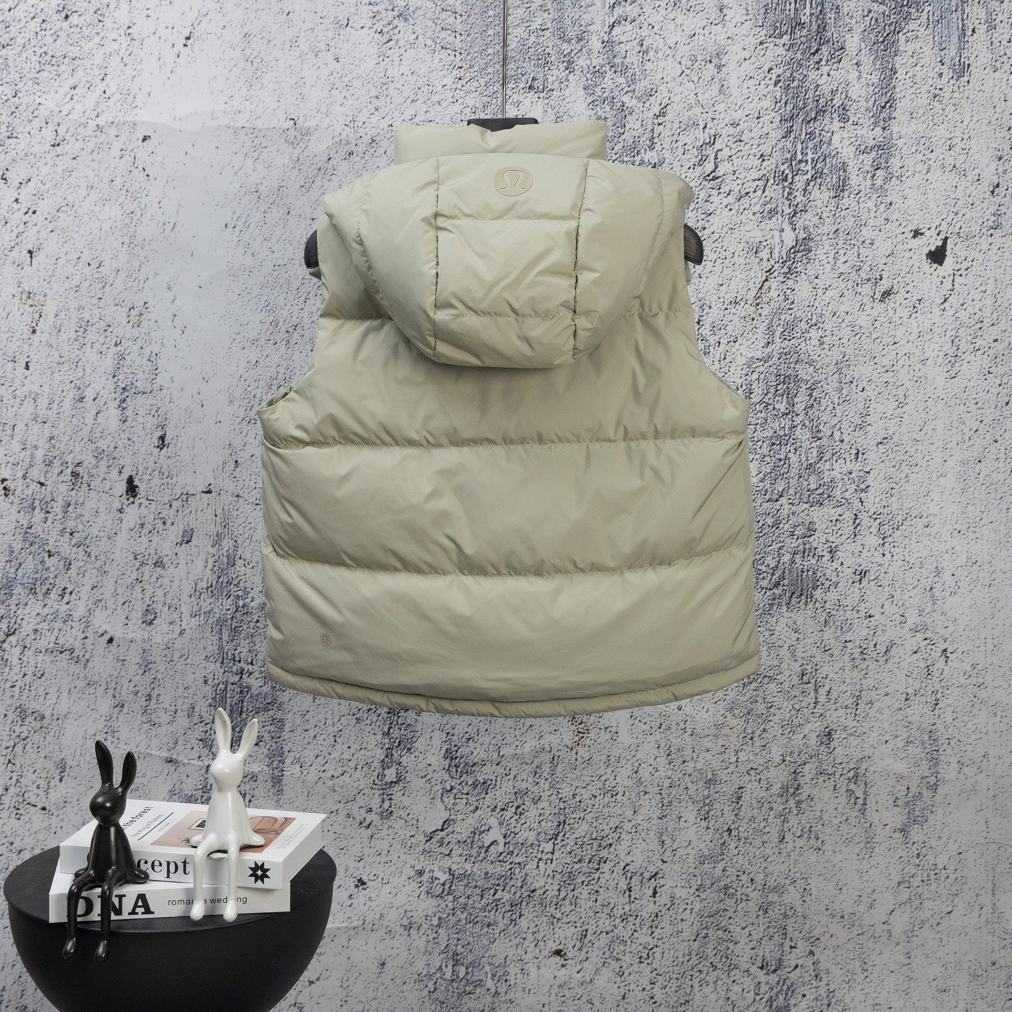 Light green sleeveless puffer vest with hood and front pockets