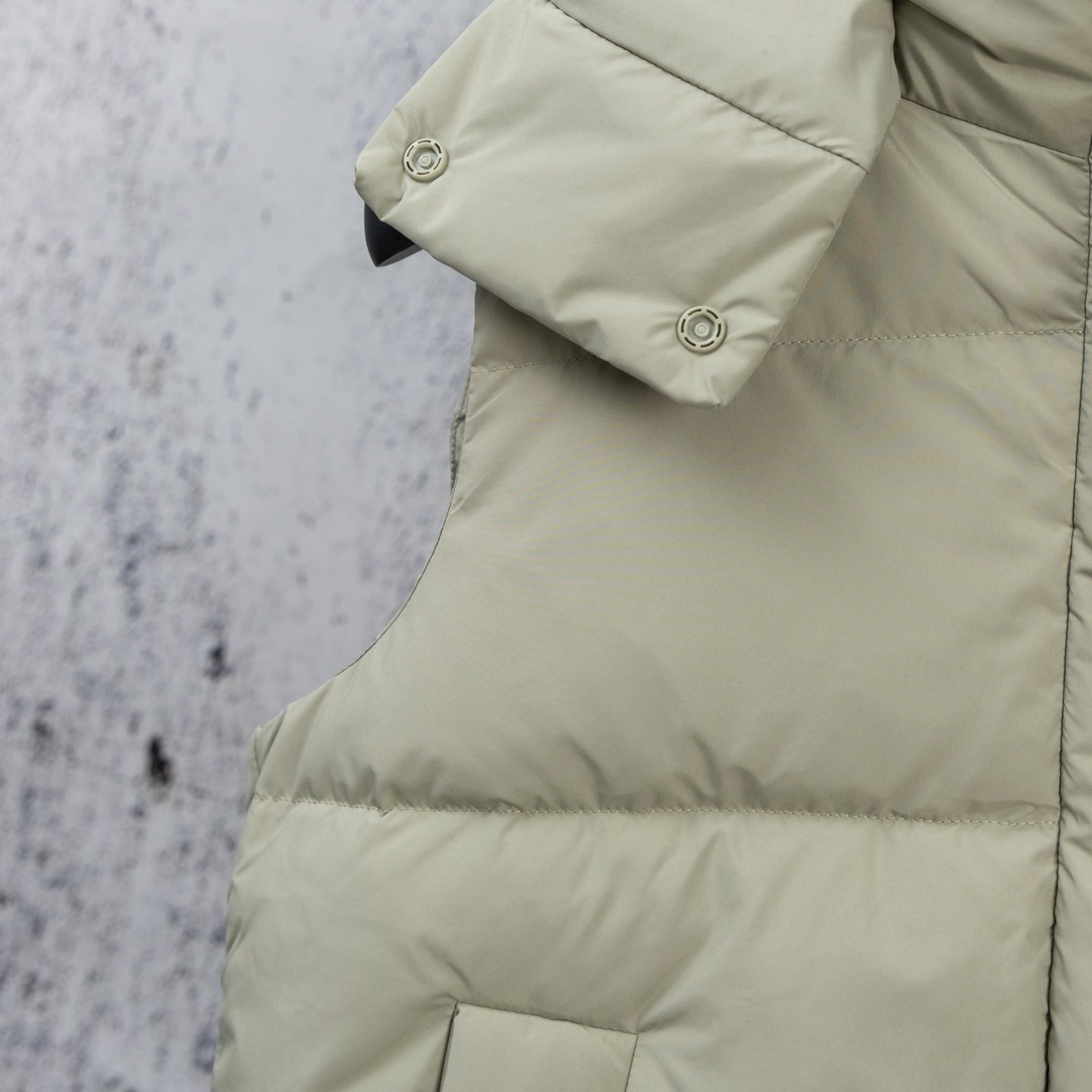 Light sage puffer vest with buttoned cuff detail and quilted front panel