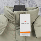 Light sage puffer vest with standing collar and hanging brand tag at the chest