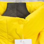 Yellow puffer jacket hood with front snap closure, partial product tag