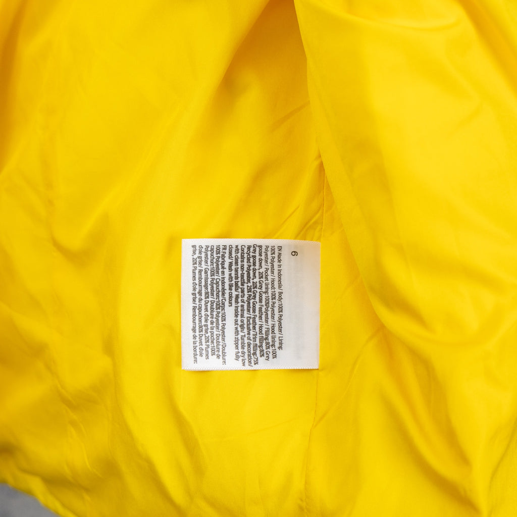 Yellow puffer jacket inner label close-up on quilted fabric