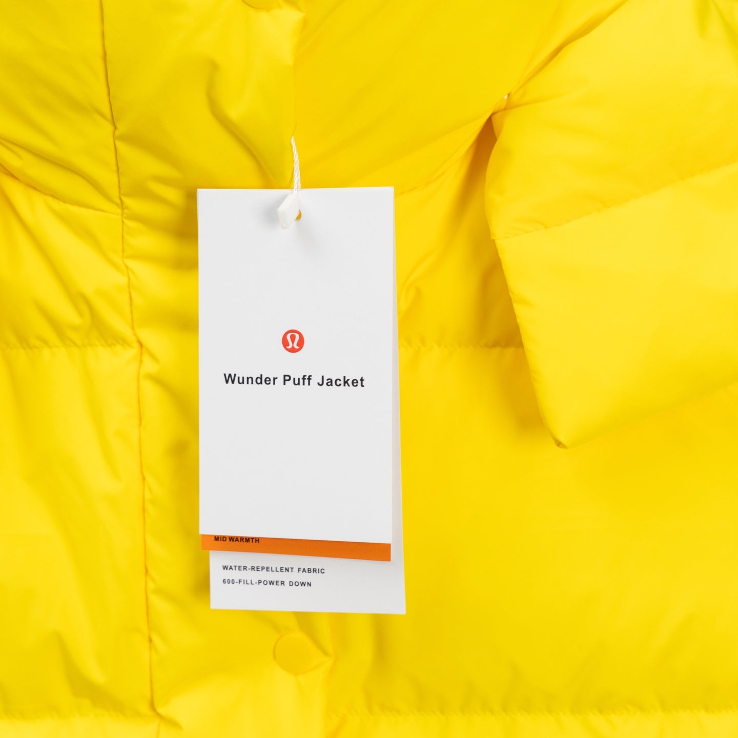 Yellow puffer jacket with hanging tag showing brand and care details