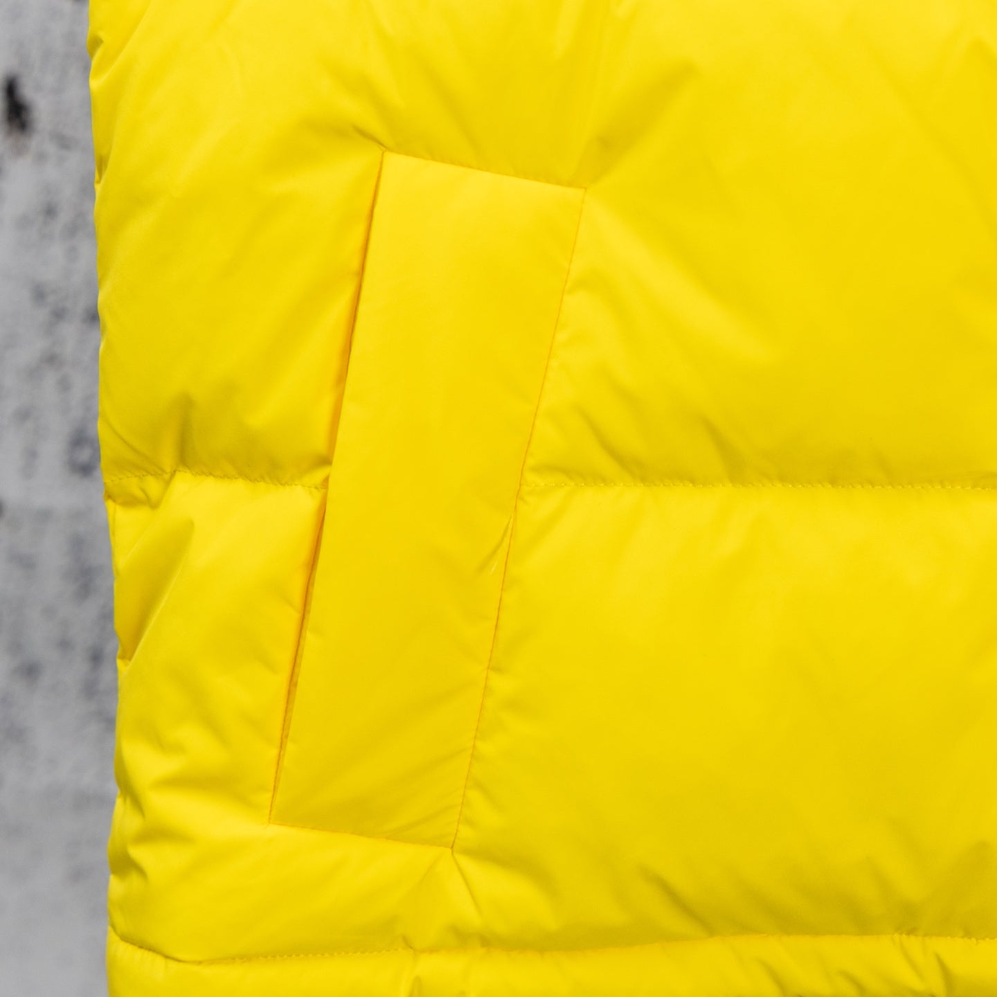 Yellow puffer jacket paneling with quilted blocks and stitched seams