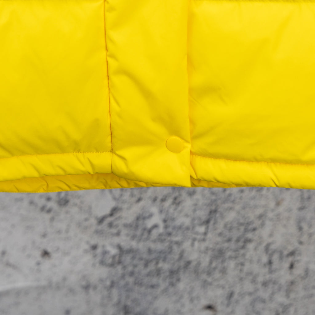 Yellow puffer jacket lower front panel with snap and stitched seams