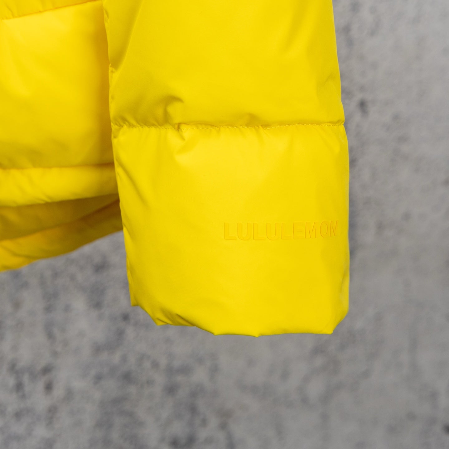 Yellow puffer jacket hem with subtle logo embossing