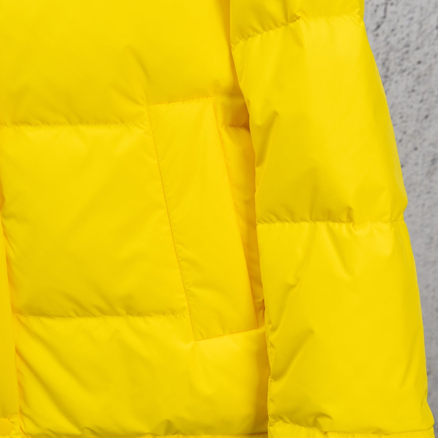 Yellow puffer jacket side seam and quilting, no hood visible