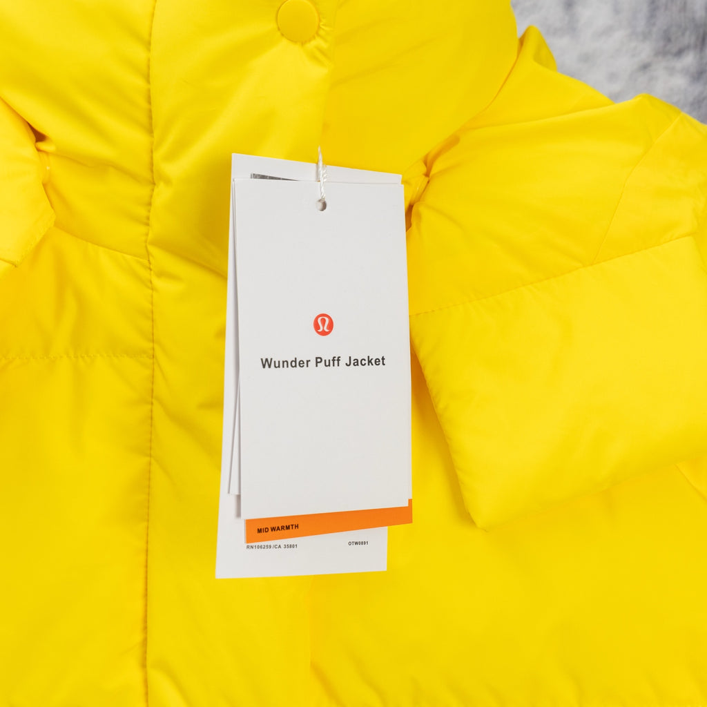 Yellow puffer jacket detail with hang tag and smooth quilted panels