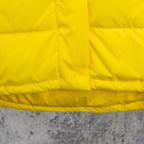 Yellow puffer jacket front yoke with horizontal quilting and circular snap