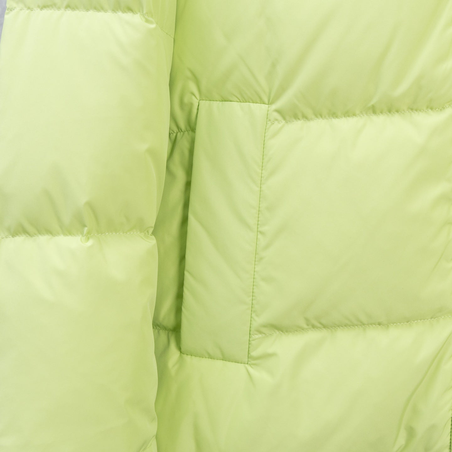 Light green puffer jacket sleeve and quilted front panel stitching