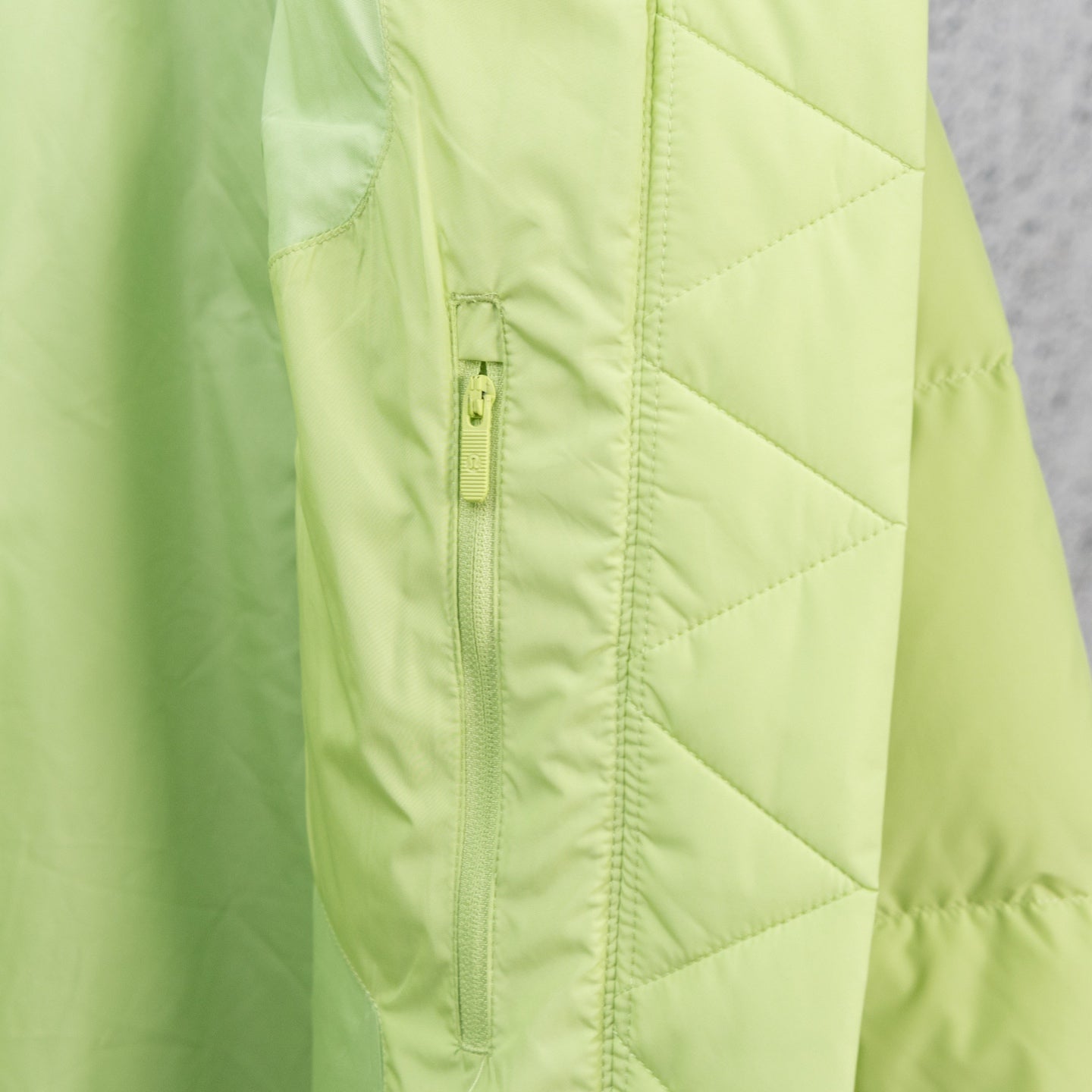 Lime green puffer jacket front seam with center zipper and quilted panels