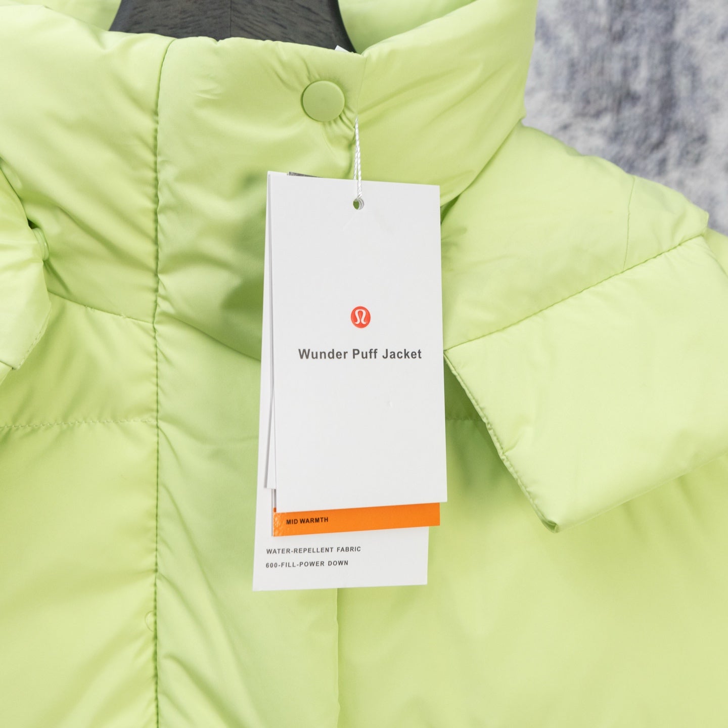 Lime green puffer jacket with front button placket and hanging product tags
