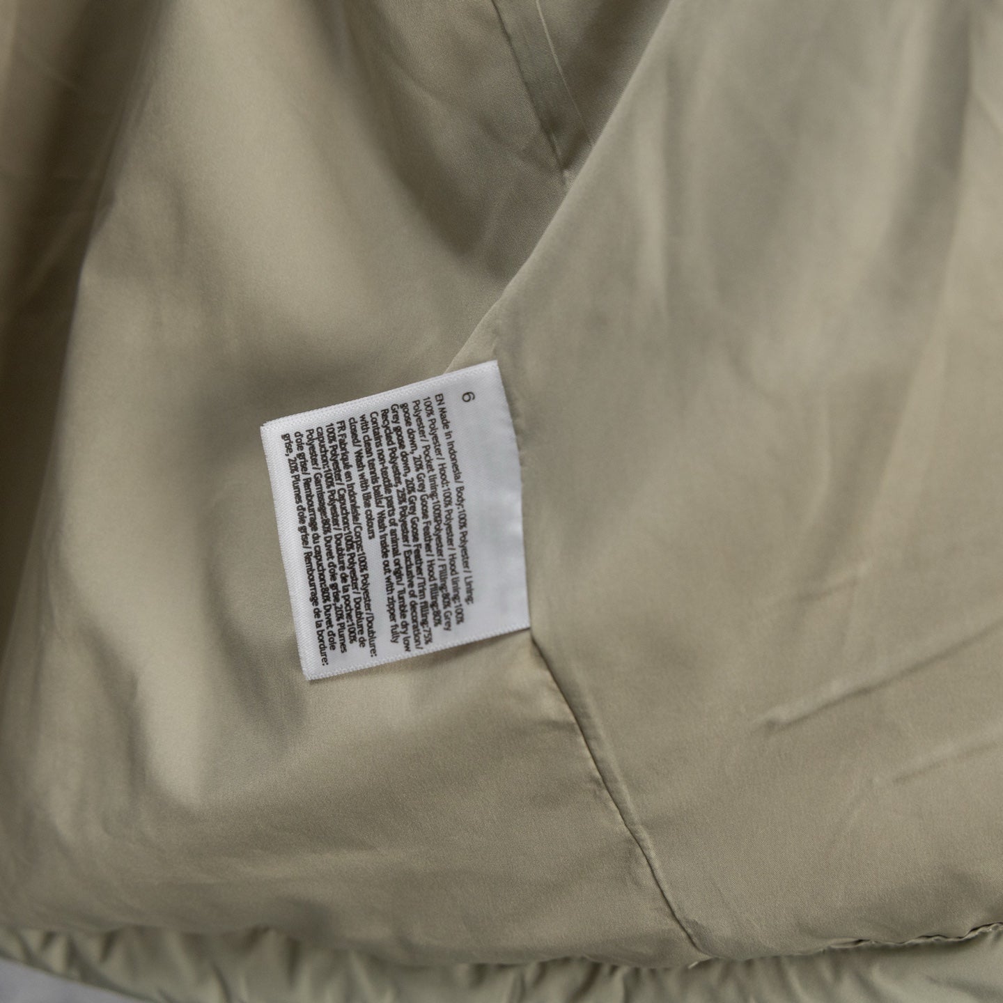 Beige puffer jacket front with sewn care label on chest