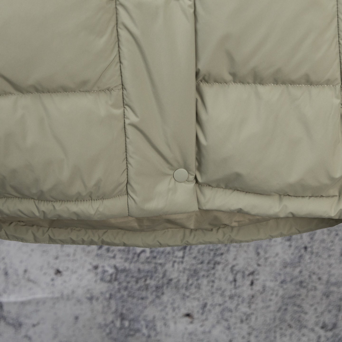 Light olive puffer jacket hem with center button and quilted panel seams