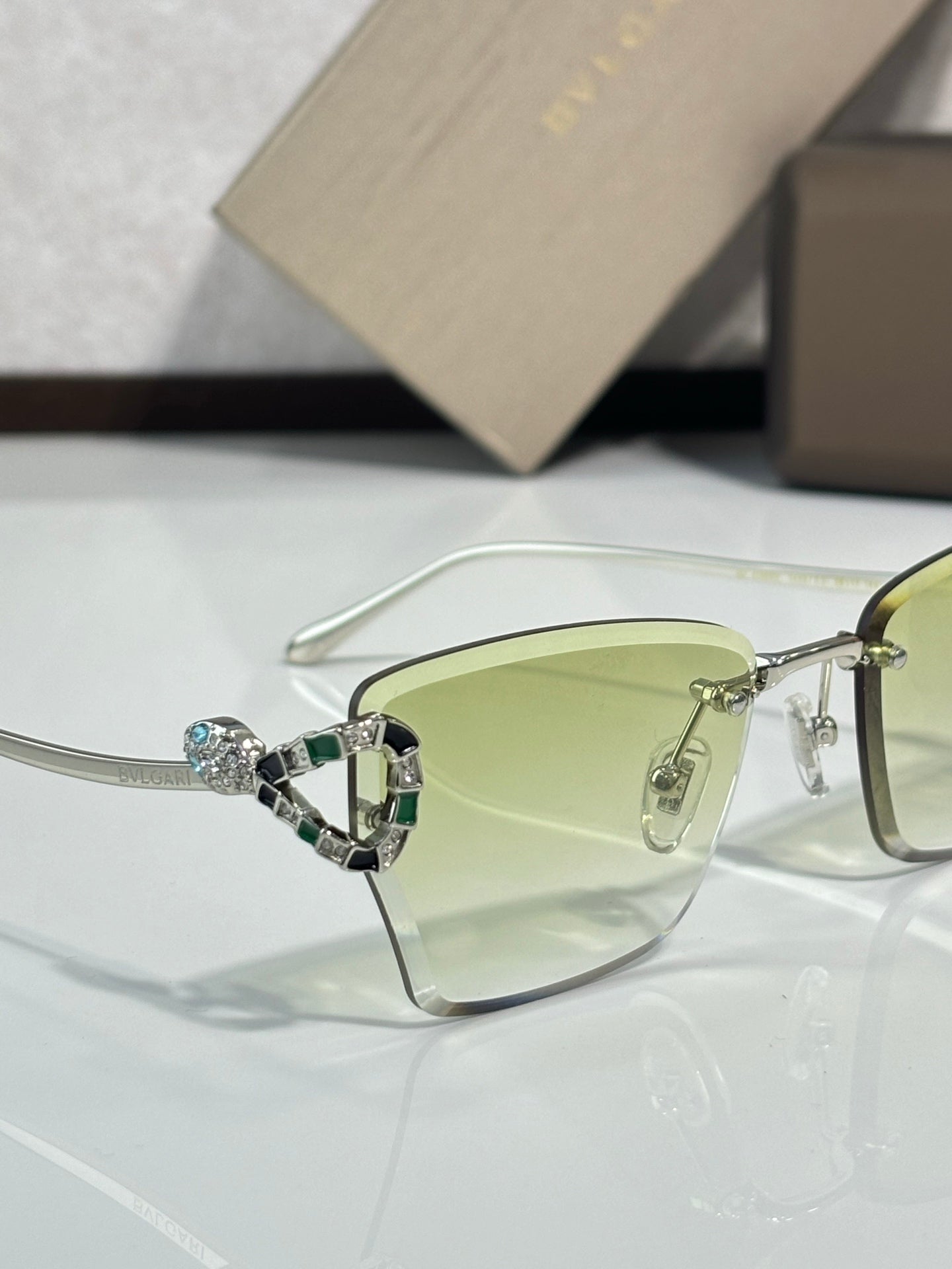Close-up of Bvlgari eyeglasses with light green tinted lens and metal frame
