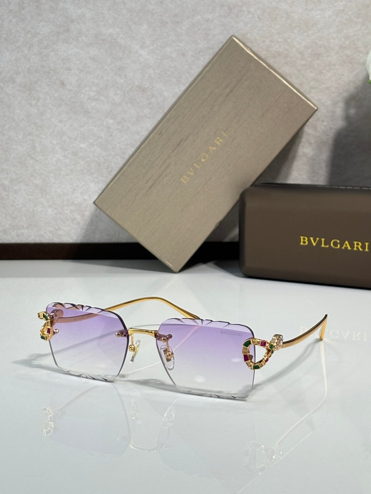 Bvlgari sunglasses with lilac-pink tinted lenses and gold frame with jeweled accents