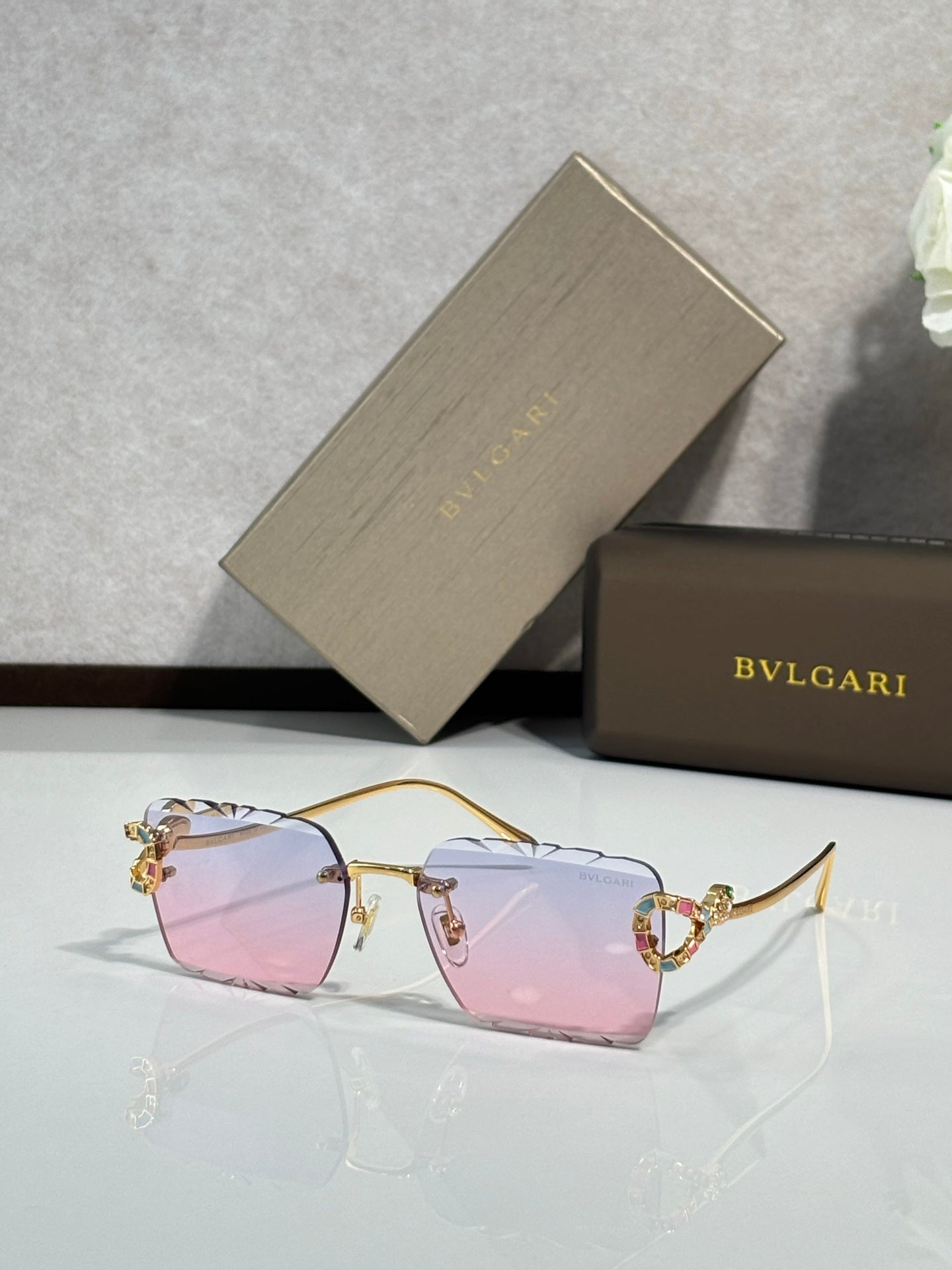 Bvlgari sunglasses with pink tinted lenses and gold frame with jeweled temple details