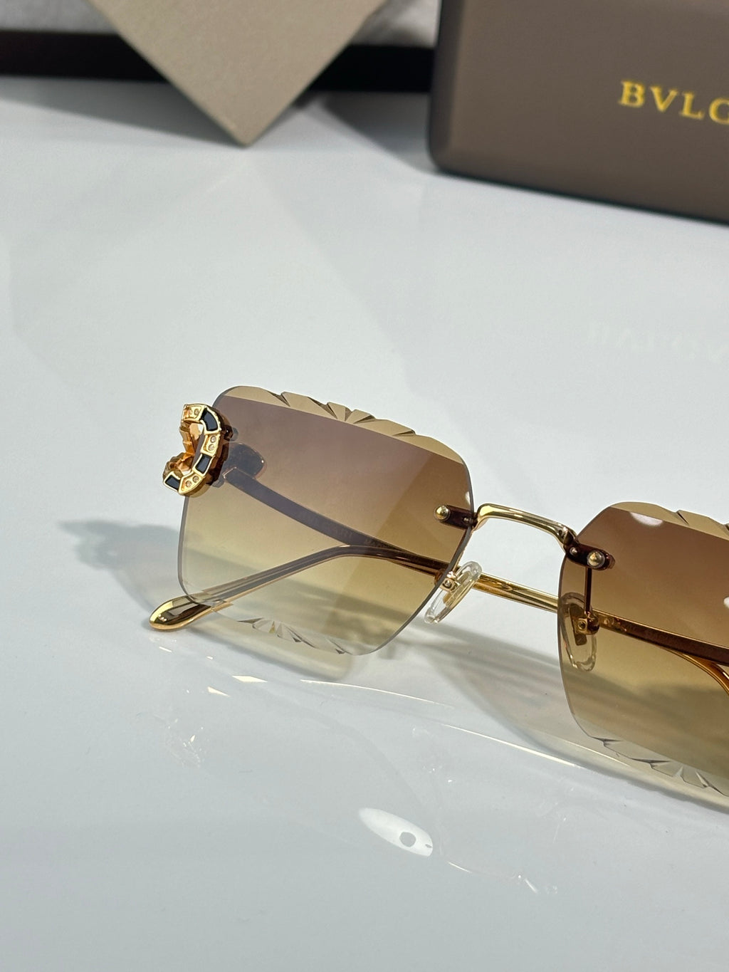 Bvlgari sunglasses side view with amber tinted lens and gold frame and hinge detail