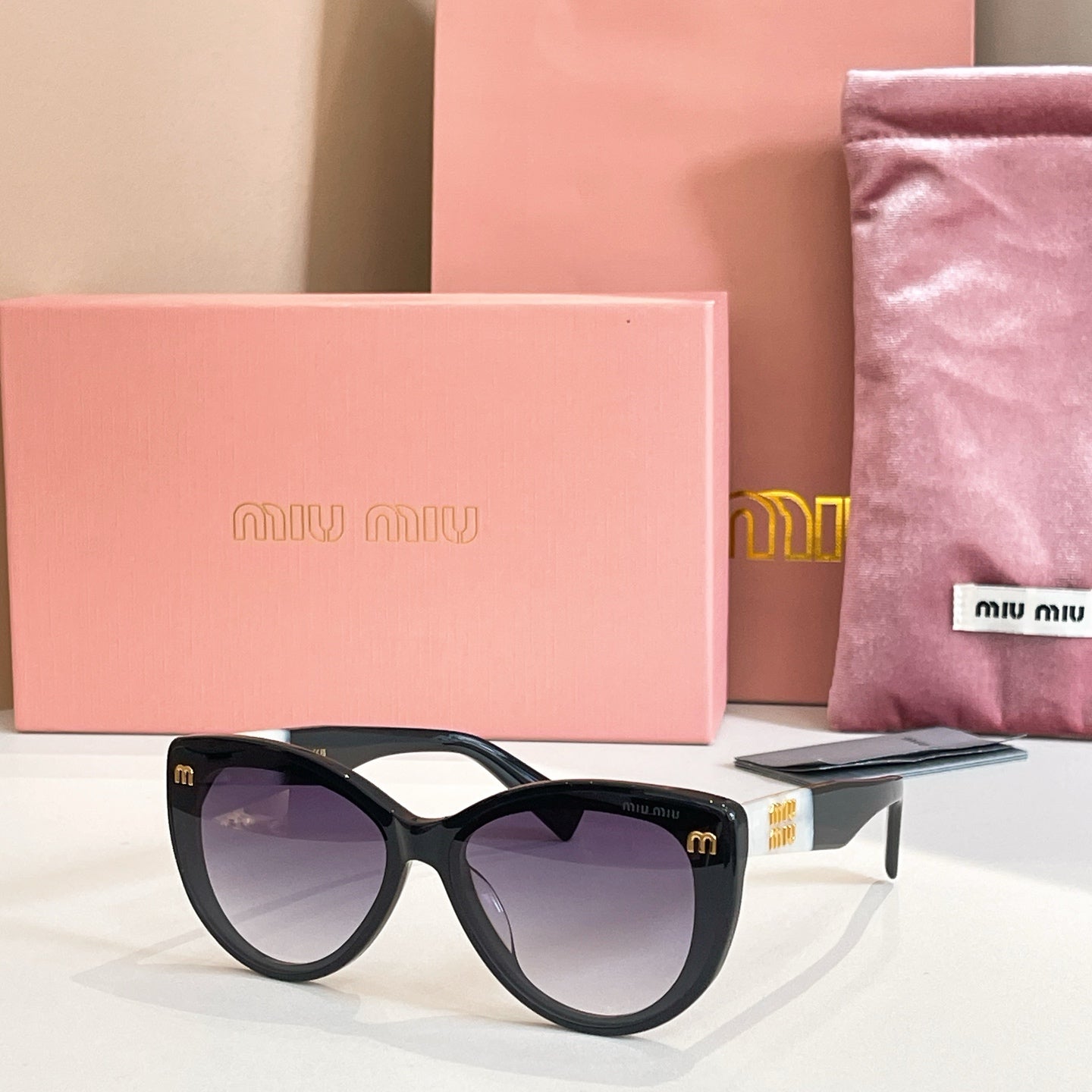 MiuMiu cat-eye sunglasses with black frames and purple-tinted lenses.