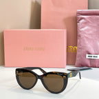 MiuMiu cat-eye sunglasses with black frames and amber-tinted lenses.