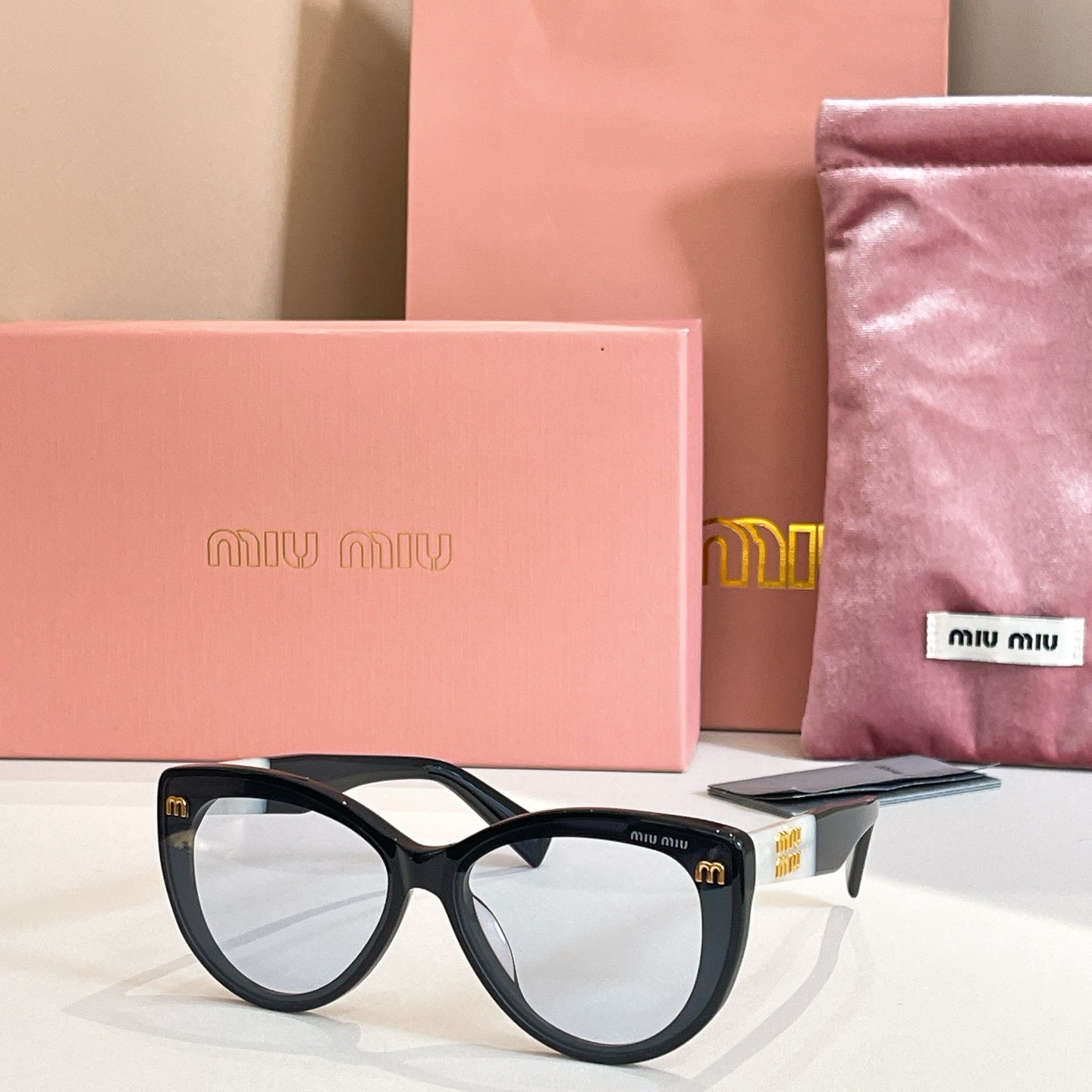 MiuMiu cat-eye sunglasses with black frames and gray-tinted lenses.