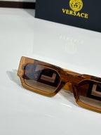 Rectangular sunglasses side view with amber frames and tinted lenses, gold logo detail