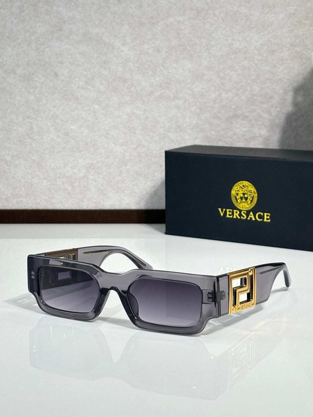 Rectangular sunglasses with dark brown frames, smoky gray lenses, gold temple accents