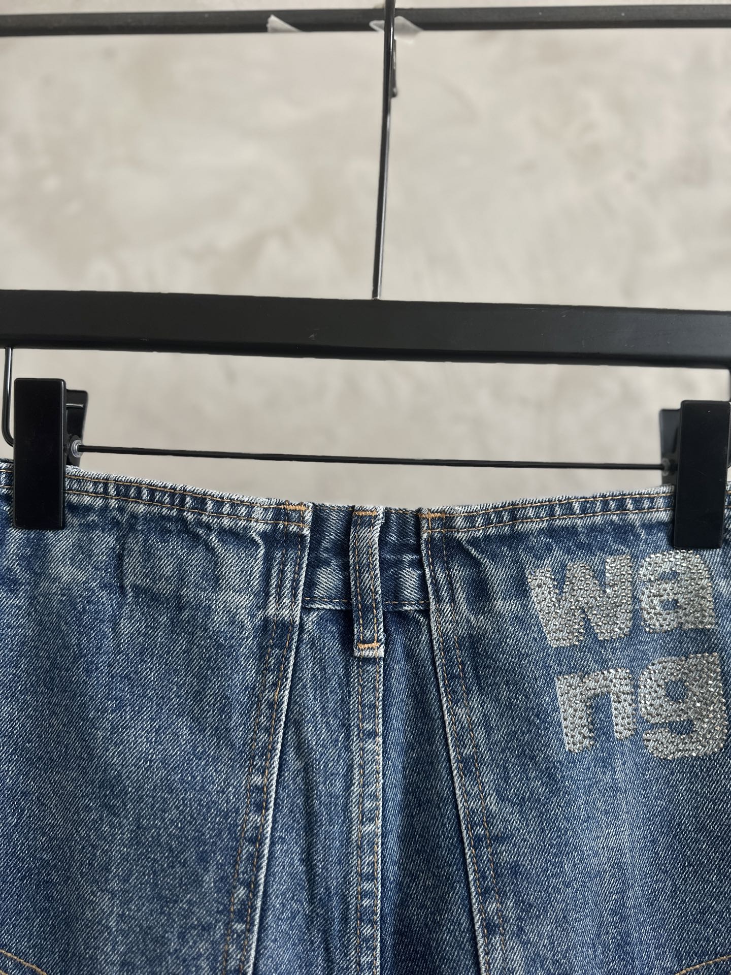 Light blue denim pants, button-and-zip front, waistband logo print