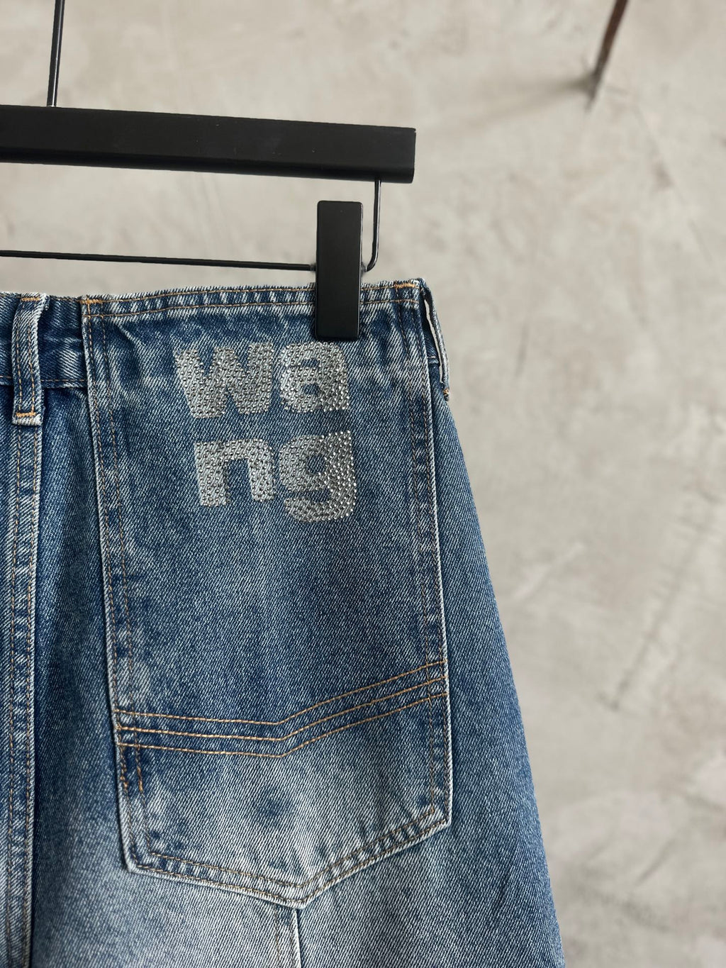 Light blue denim pants back patch pocket with large 'we...ng' graphic