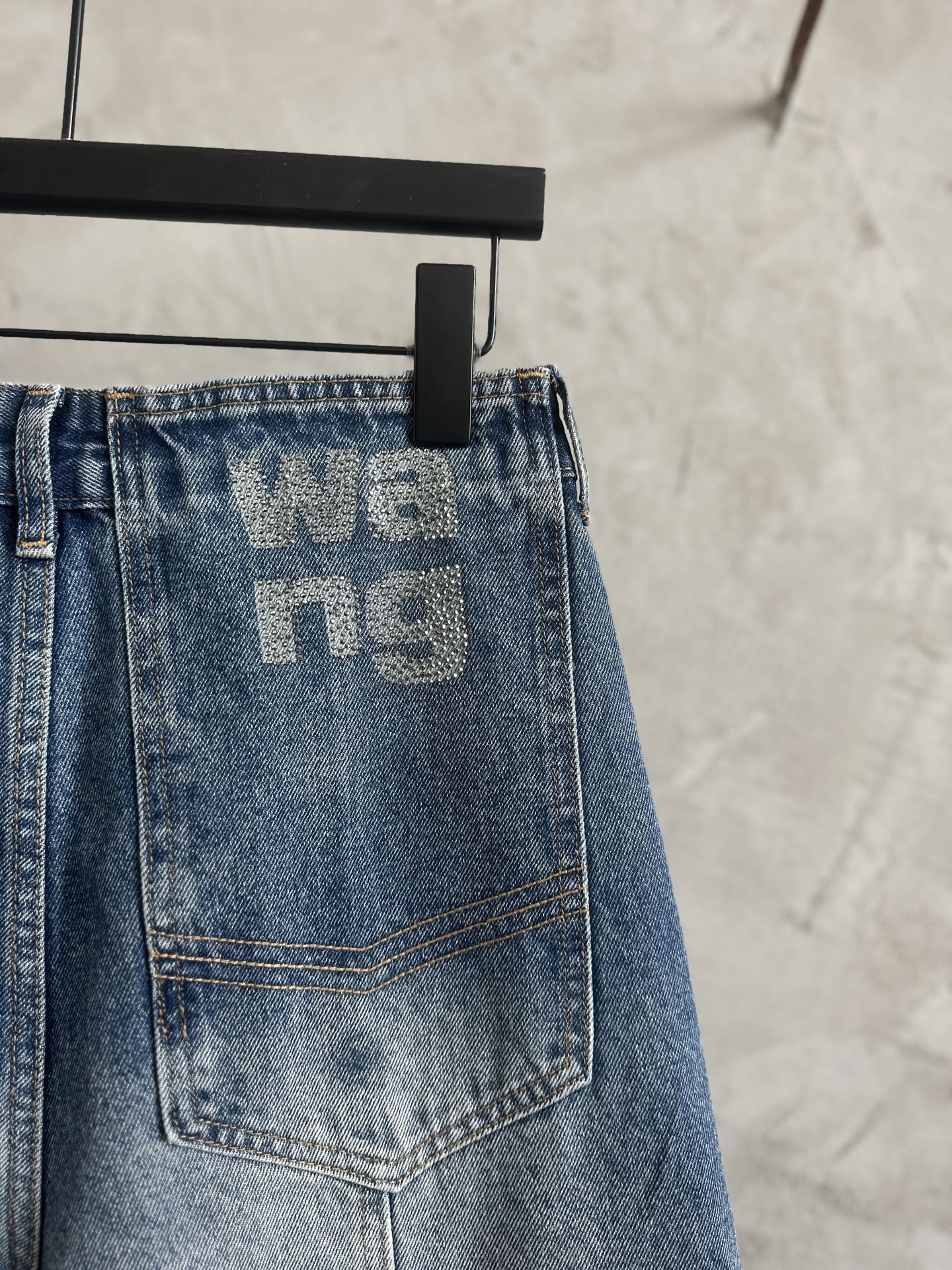 Light blue denim pants back patch pocket with large 'we...ng' graphic