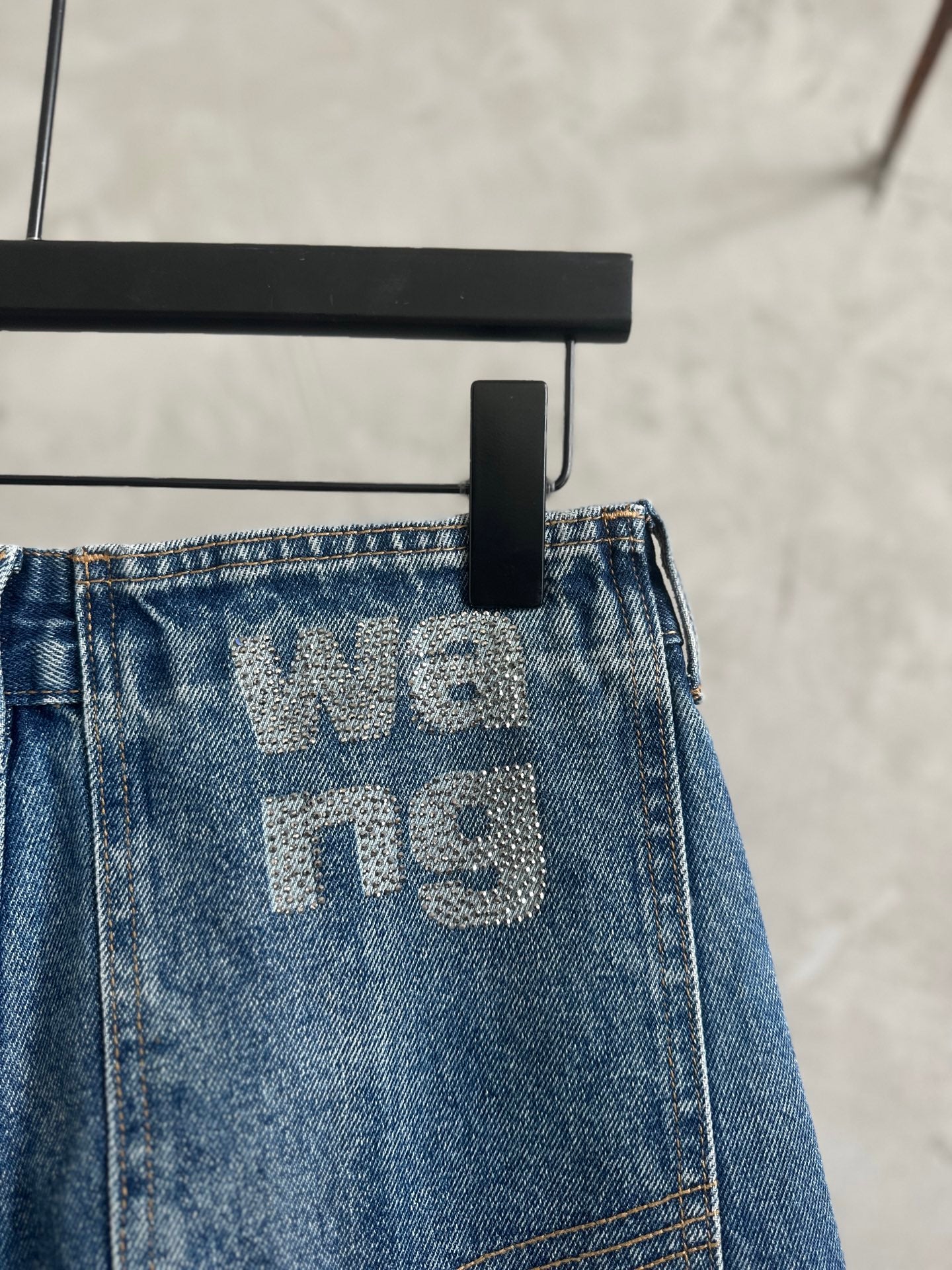 Light blue denim pants waistband with large 'We' graphic and belt loops
