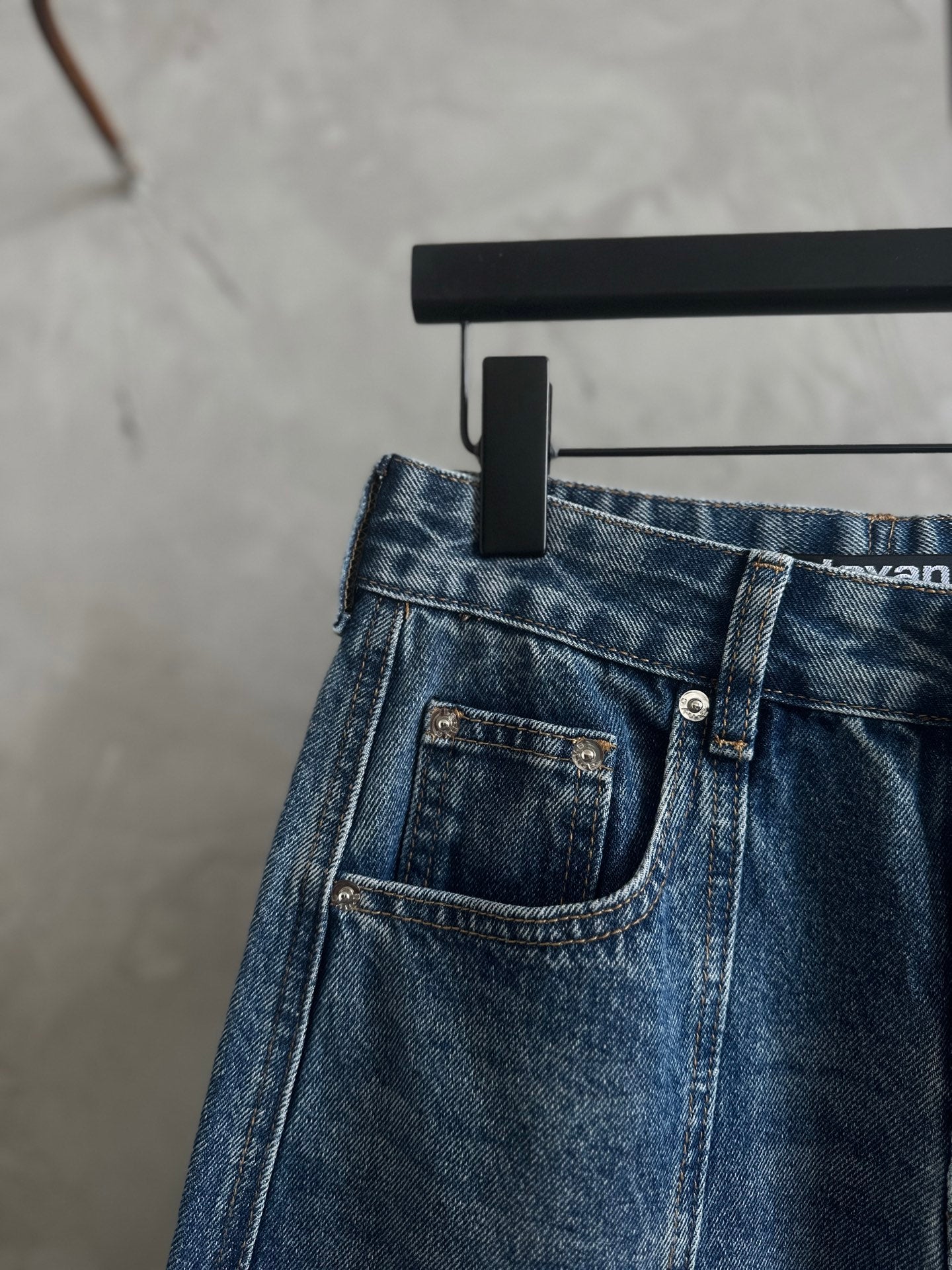 Blue denim pants with front pockets and metal-button closure