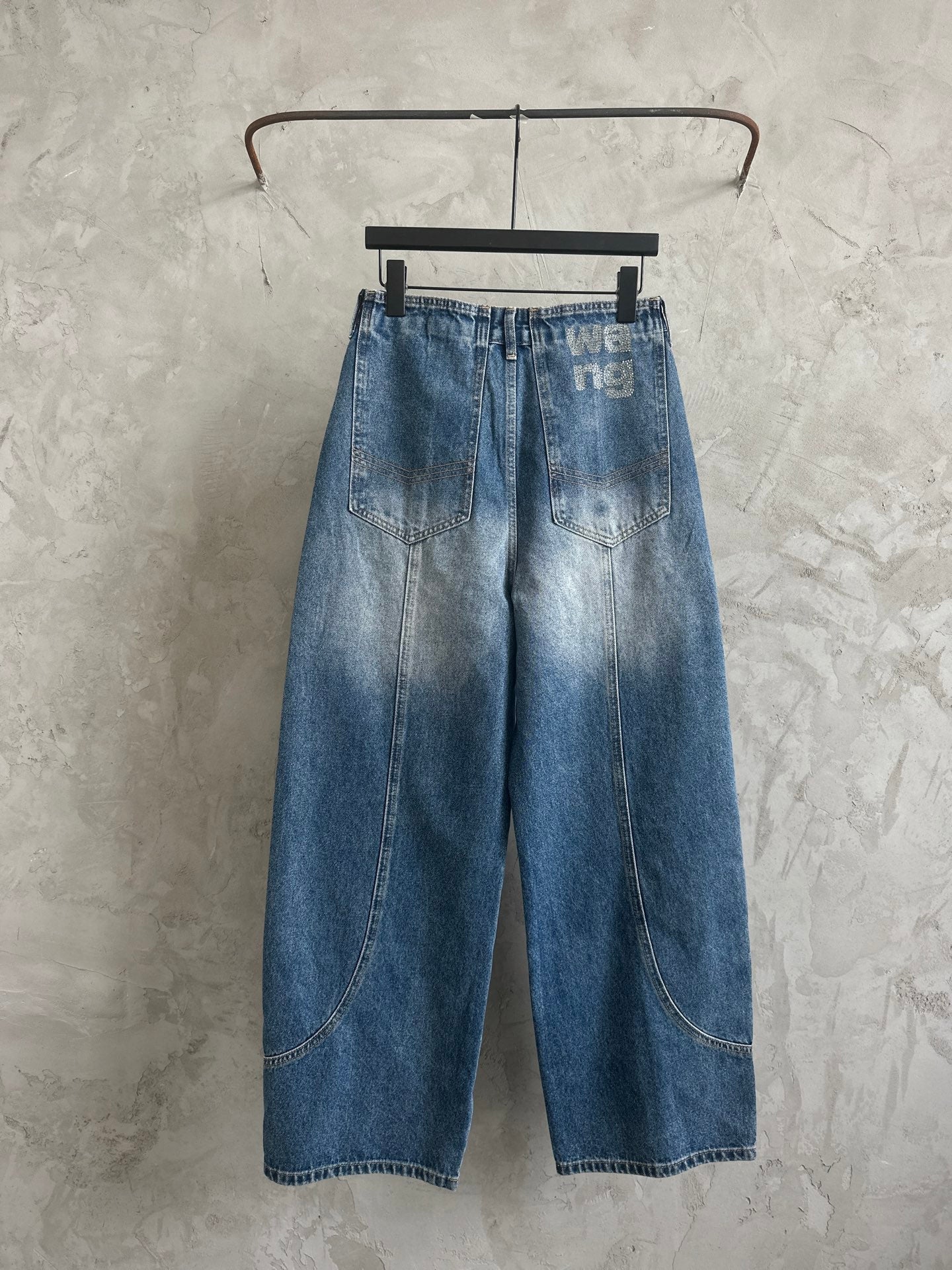 Light blue denim pants with wide-leg cut, belt loops, and back graphic print