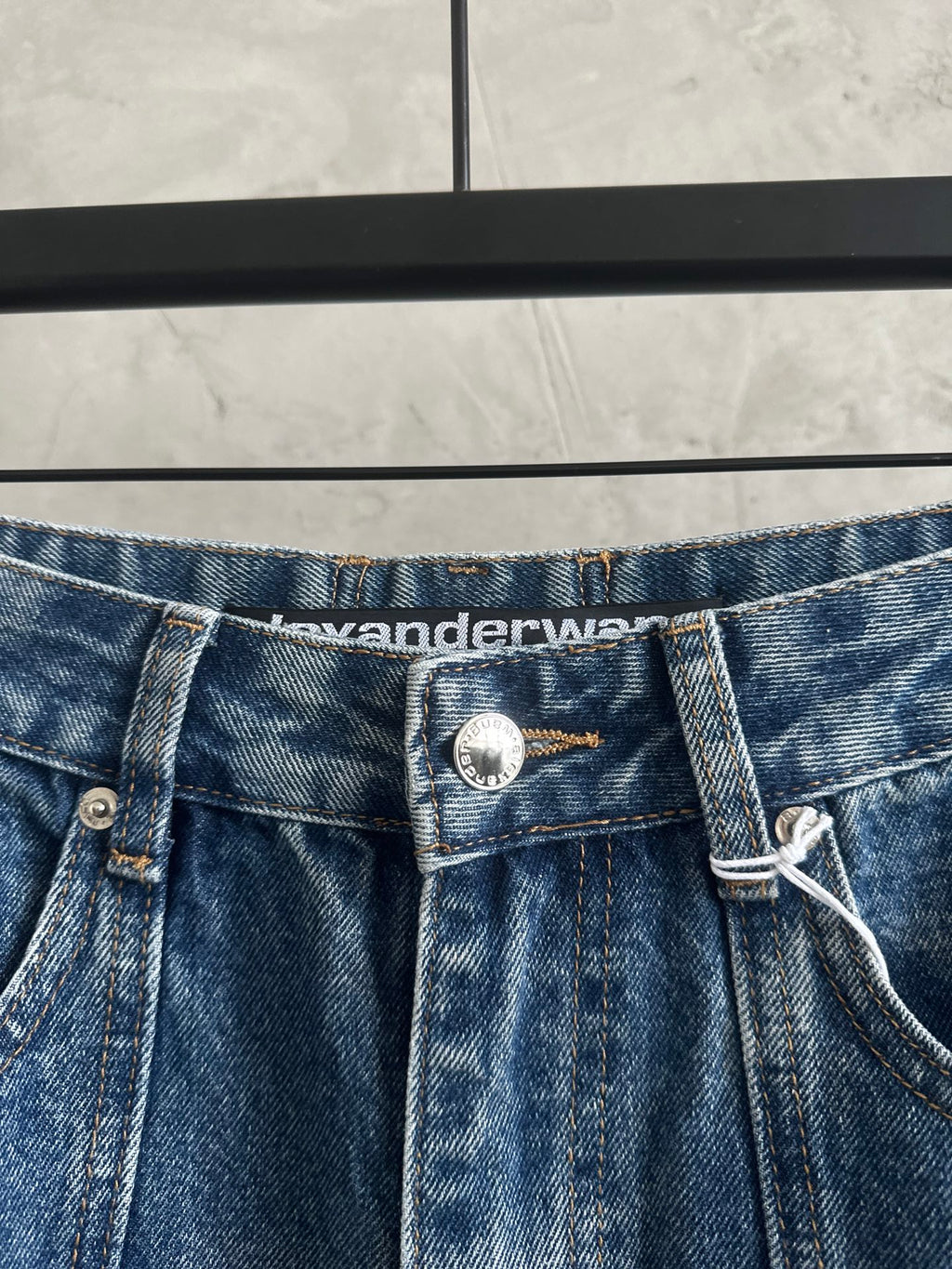 Blue denim pants waistband with button closure and waistband logo patch