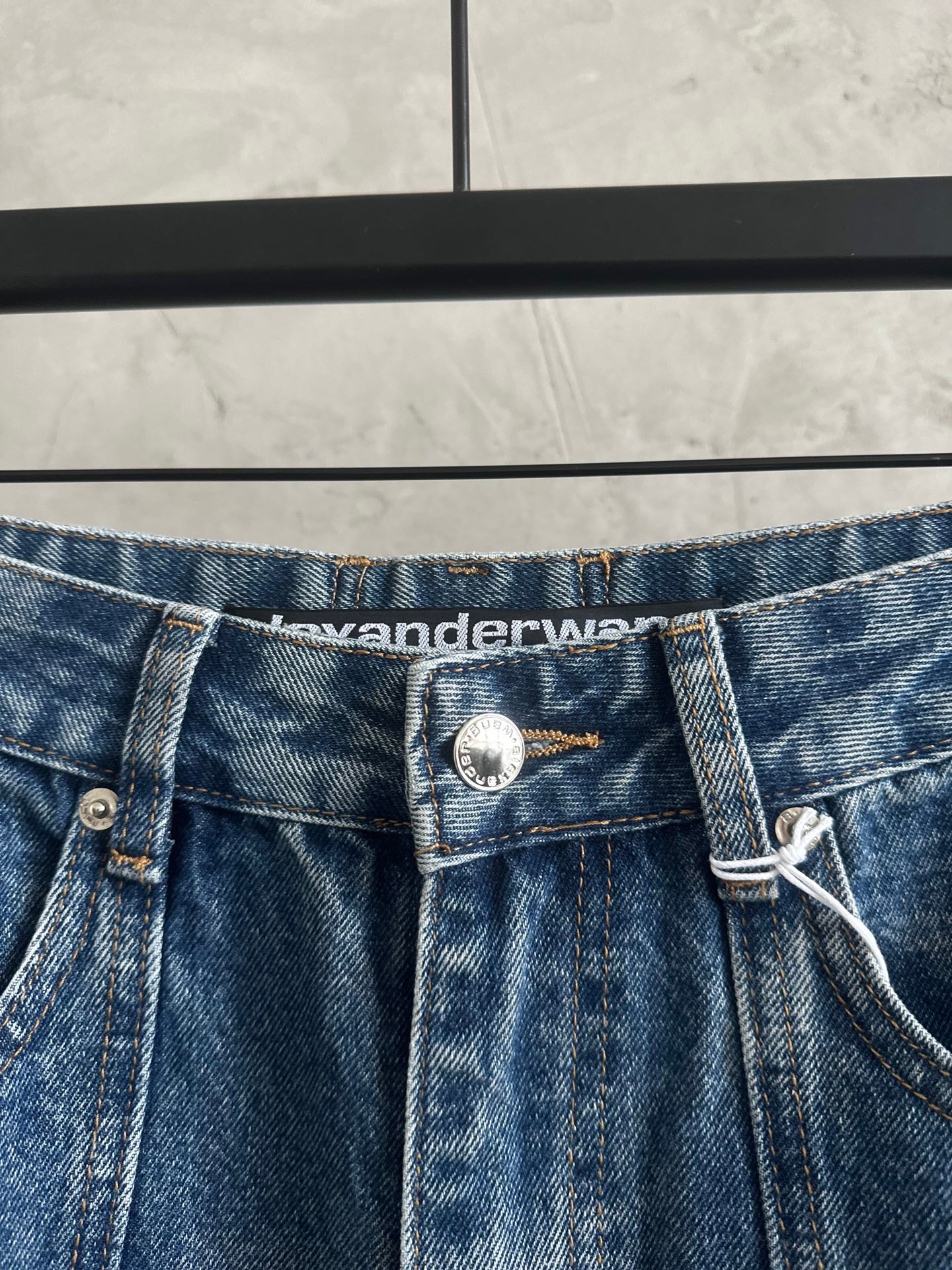 Blue denim pants waistband with button closure and waistband logo patch