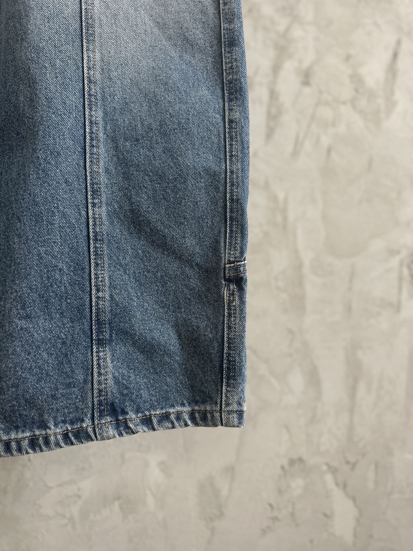 Blue denim pant leg with stitched hem detail