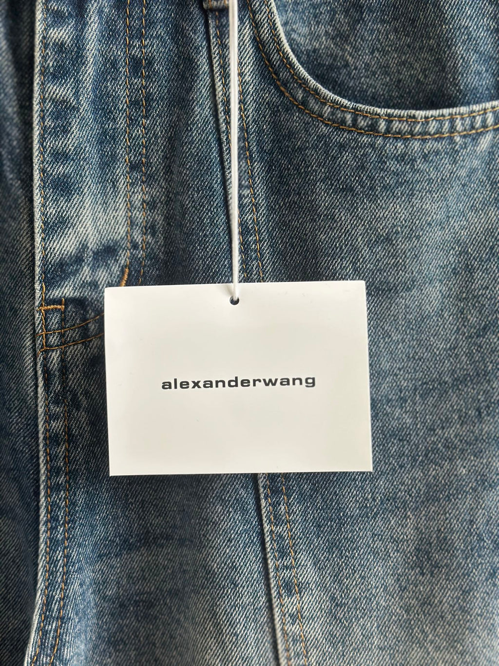 Blue denim pants with “alexanderwang” hang tag on belt loop