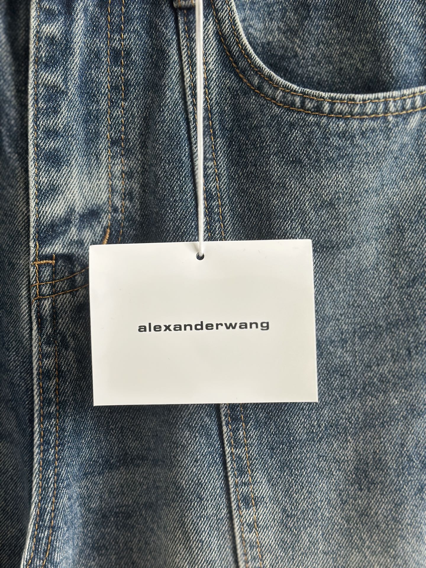 Blue denim pants with “alexanderwang” hang tag on belt loop