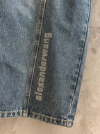 Blue denim pants with vertical “alexanderwang” label near hem