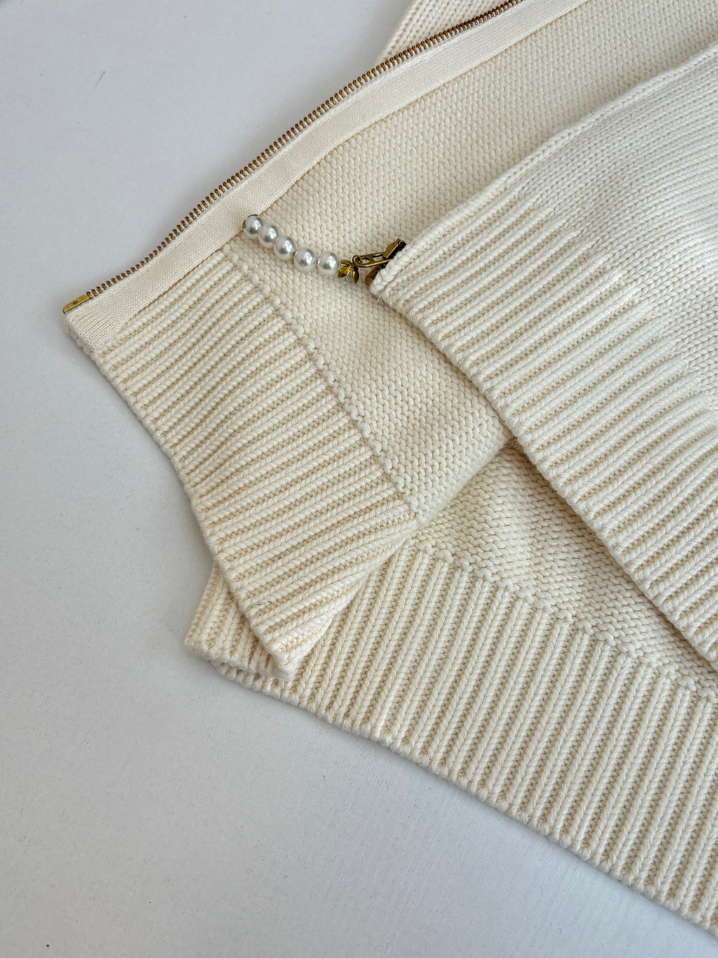 White knit sweater front with zipper track and small pearl-bead trim