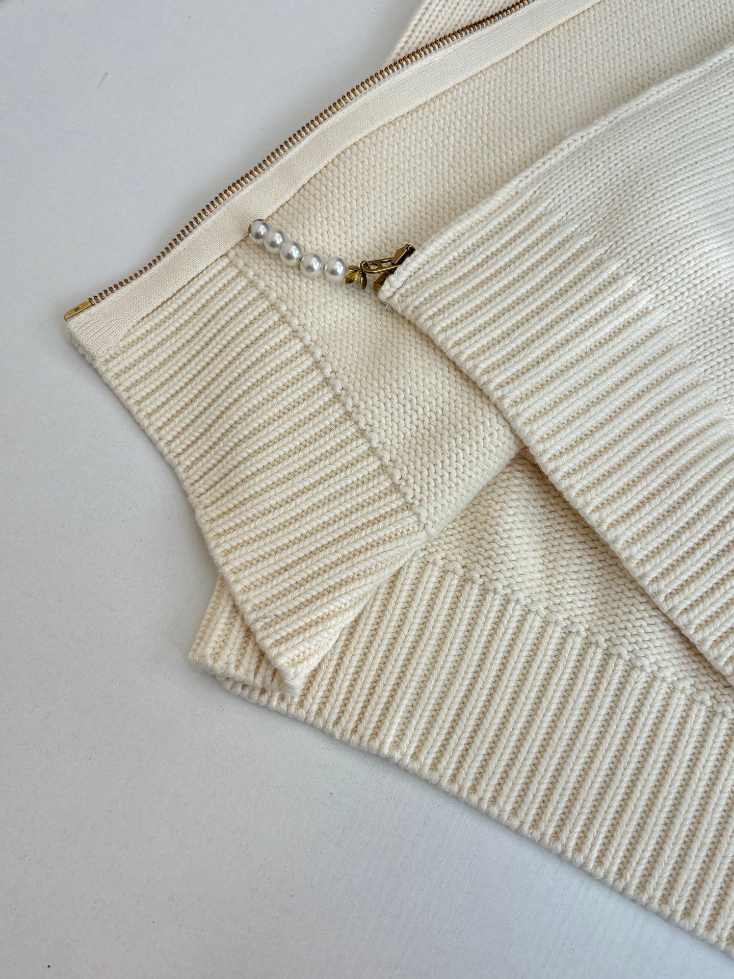 White knit sweater front with zipper track and small pearl-bead trim