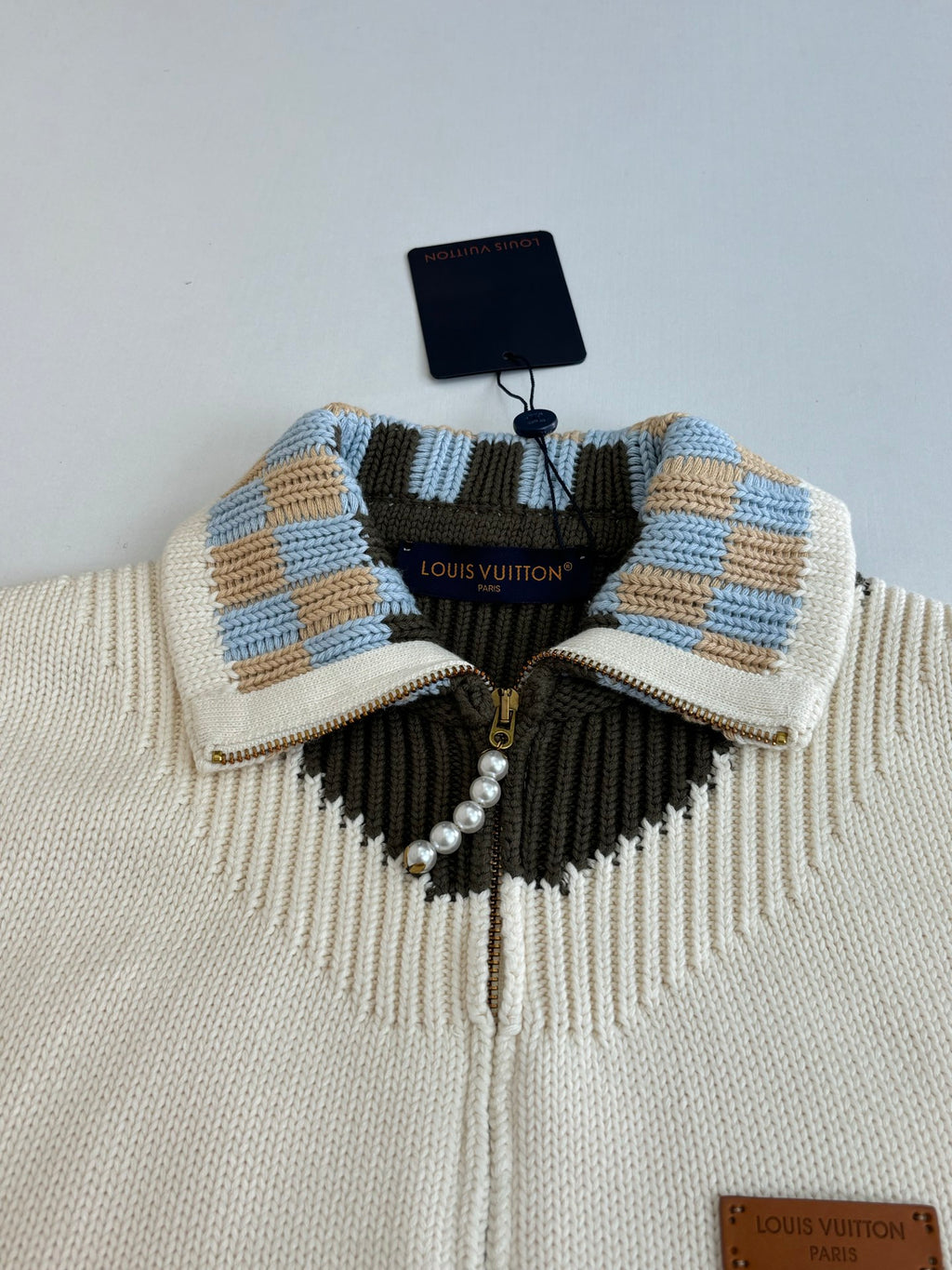 White knit sweater collar with blue plaid stripes, black yoke, and gold zipper