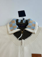 White knit sweater collar with blue plaid stripes, black yoke, and gold zipper